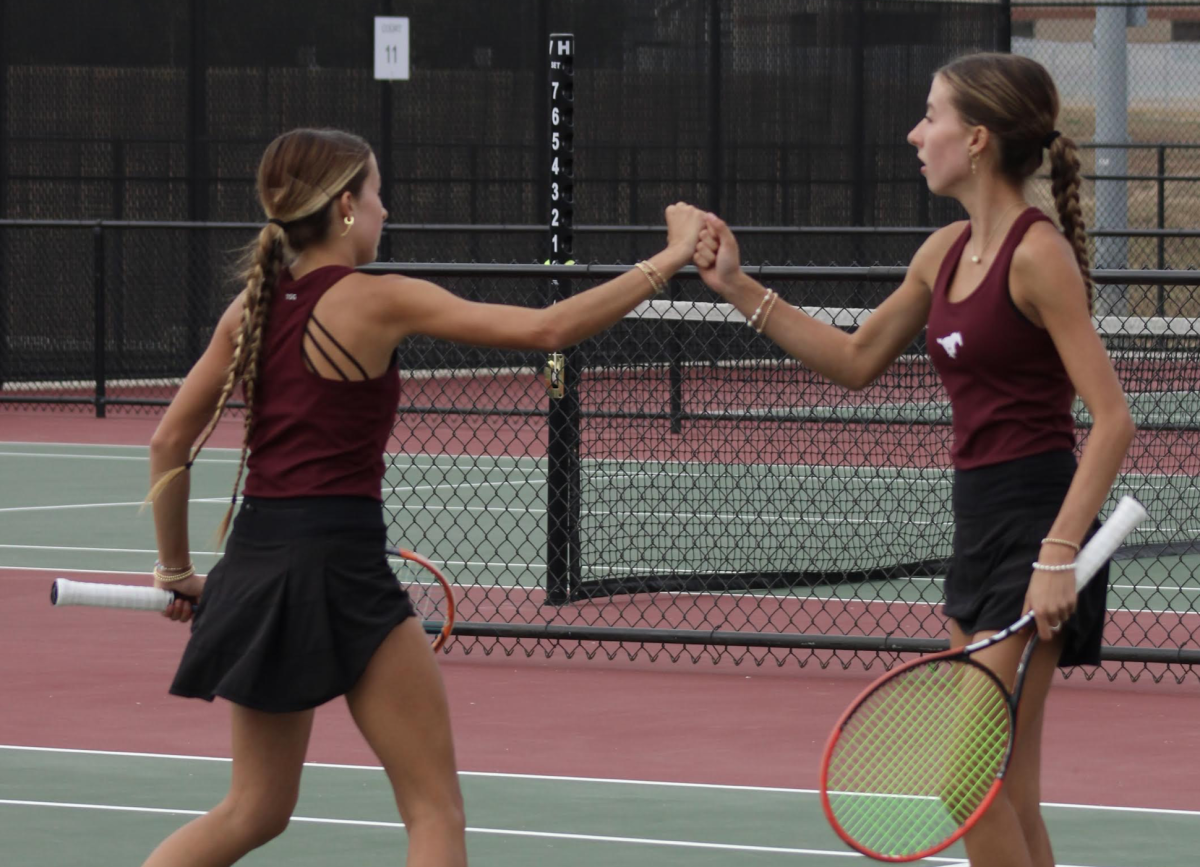 Sisters Addison and Mallory Renfro encourage each other during a match in the state tennis tournament in Wichita last Saturday. They placed third in doubles. 